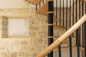 A wooden staircase with a stone wall background. - Chic Apartment Near Ménilmontant & Père Lachaise (Paris)