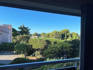 Une vue depuis une fenêtre donnant sur un quartier résidentiel, avec des arbres et un immeuble.