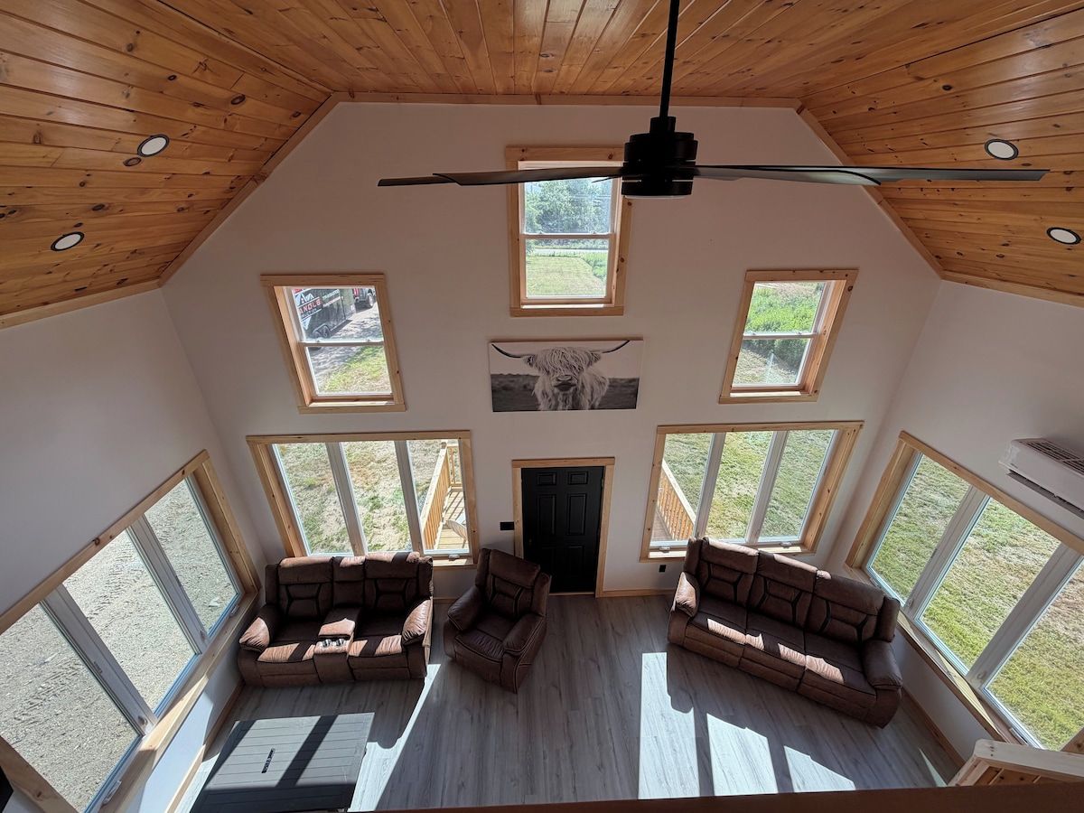 Una habitación amplia con techo alto, múltiples ventanas y un ventilador de techo.
