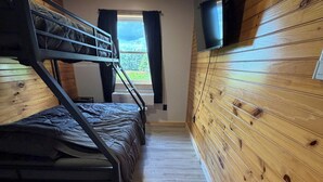A bunk bed room with wooden walls and a window. - Unwind at The Highland Sunset—a comfortable three bedroom retreat. (Princeton)