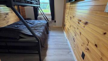 A bunk bed room with wooden walls and a window.