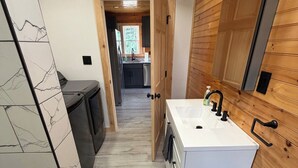 A modern bathroom with a white sink, wooden paneling, and a marble backsplash. - Unwind at The Highland Sunset—a comfortable three bedroom retreat. (Princeton)