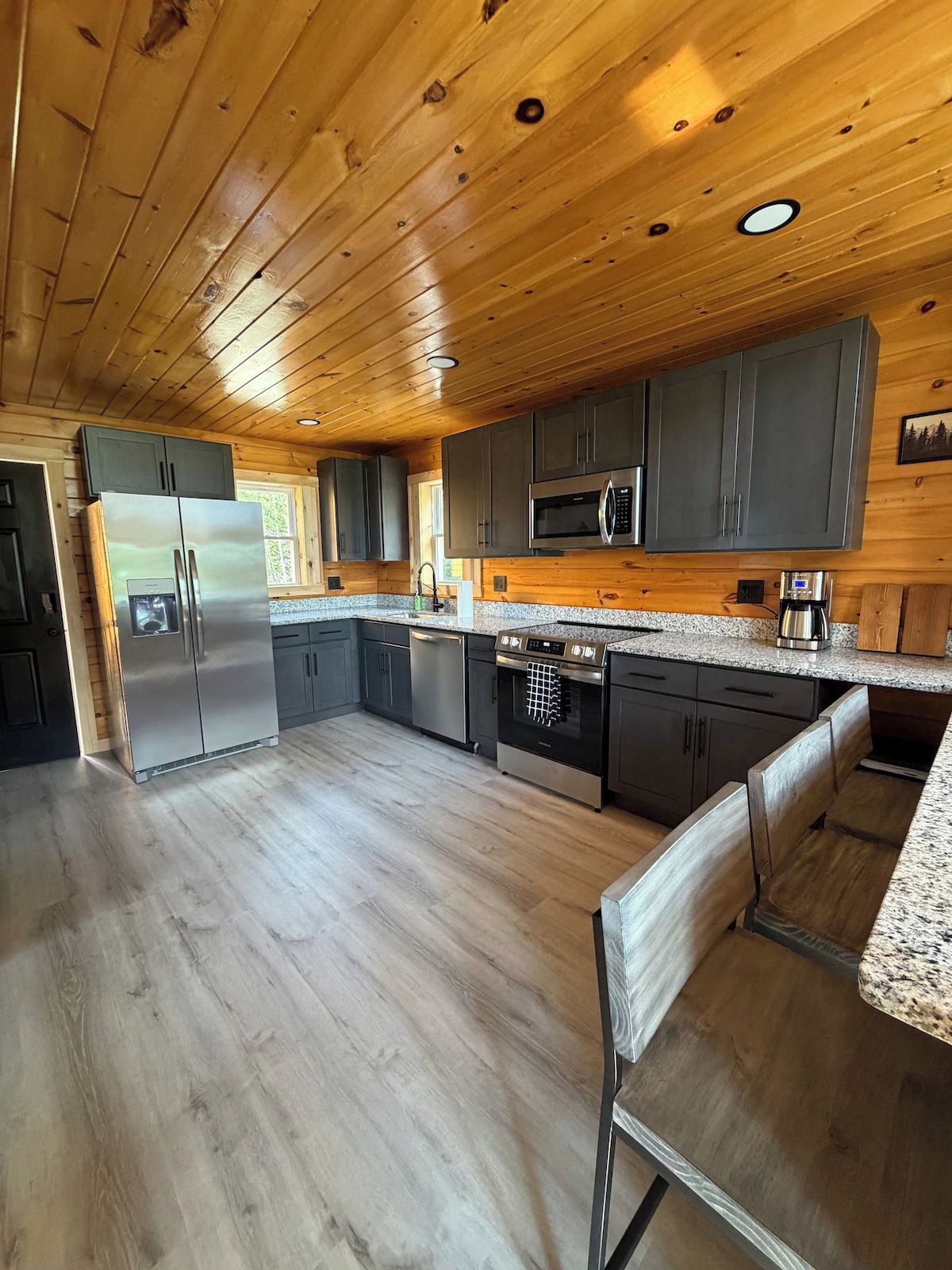 Eine moderne Küche mit Holzboden, Edelstahlgeräten und Granit Arbeitsplatten.