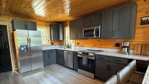 A modern kitchen with wooden ceiling, stainless steel appliances, and granite countertops. - Unwind at The Highland Sunset—a comfortable three bedroom retreat. (Princeton)