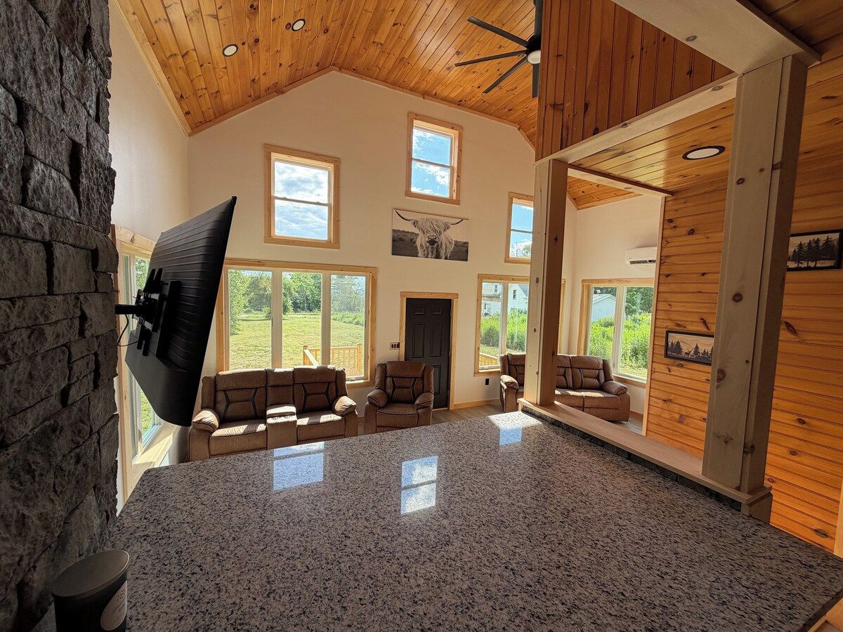 A spacious living area with a high ceiling, stone wall, and a fireplace.