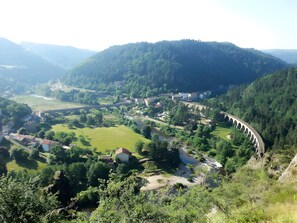 A mountainous landscape with a river, a bridge, and a series of buildings. - Gîte des Gorges de l'Allier: Mountain View, Private Terrace, and Wi-Fi (Alleyras)