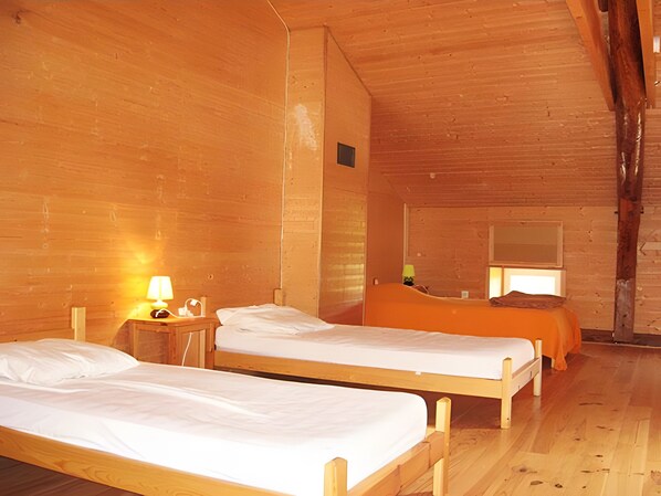 A room with two wooden beds, a nightstand with a lamp, and a window with a view. - Gîte des Gorges de l'Allier: Mountain View, Private Terrace, and Wi-Fi (Alleyras)