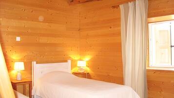 Een houten kamer met twee bedden, een raam met gordijnen en wandlampen.