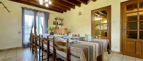 A dining area with a long table, chairs, and a wooden ceiling.