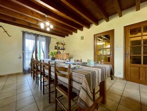 Un espace repas avec une longue table, des chaises et un plafond en bois.