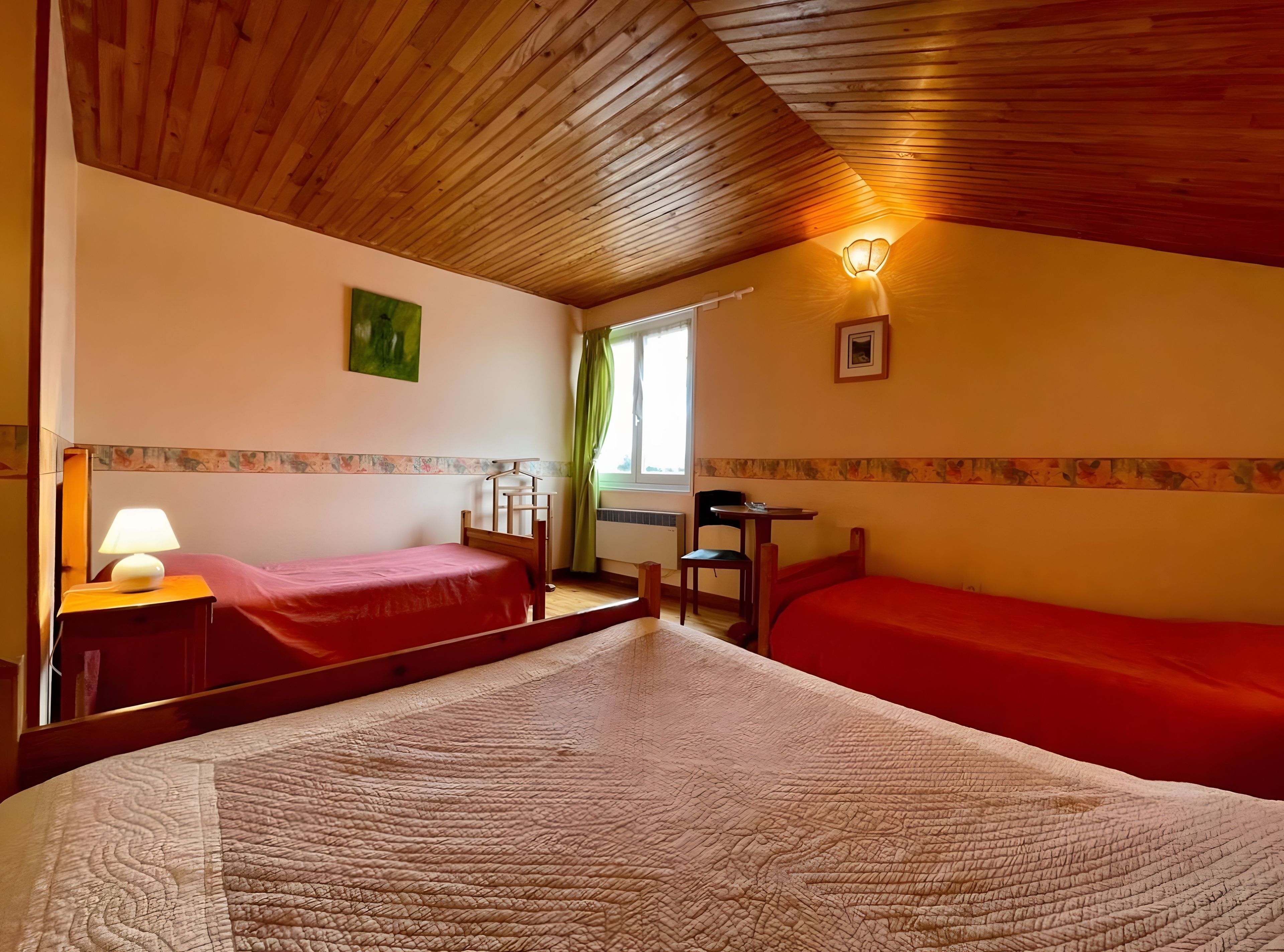 Ein Zimmer mit zwei Betten, einem Schreibtisch, einem Stuhl, einer Lampe und einem fenster mit Vorhängen.