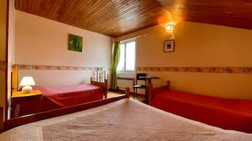 Ein Zimmer mit zwei Betten, einem Schreibtisch, einem Stuhl, einer Lampe und einem fenster mit Vorhängen.