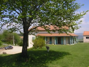 Une maison avec un toit en tuiles, une pelouse et un arbre.