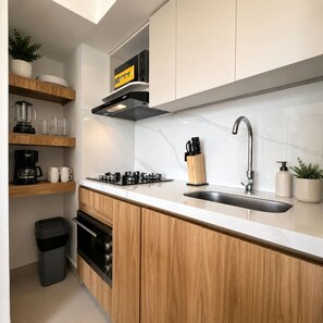 A modern kitchen with wooden cabinets, a stainless steel sink, and a built-in stove. - Coconut Palm | City Views, Marbella Beach & Pool (Cartagena)