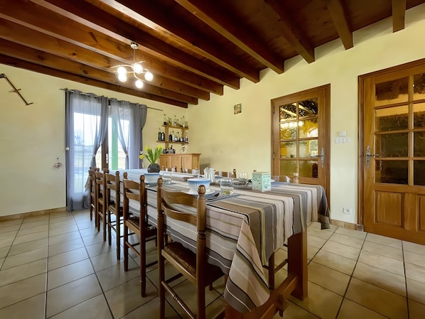 A dining area with a long table, chairs, and a wooden ceiling.