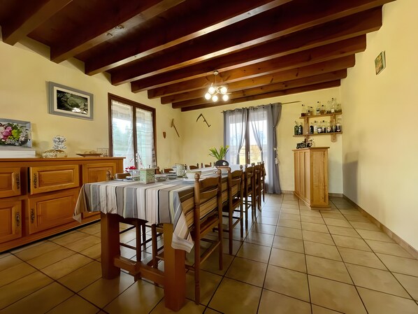 A dining area with a wooden table and chairs, a kitchen area with cabinets, and a window with curtains.