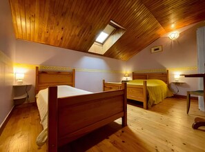 Une chambre avec deux lits en bois, une lucarne et des lampes de chevet.