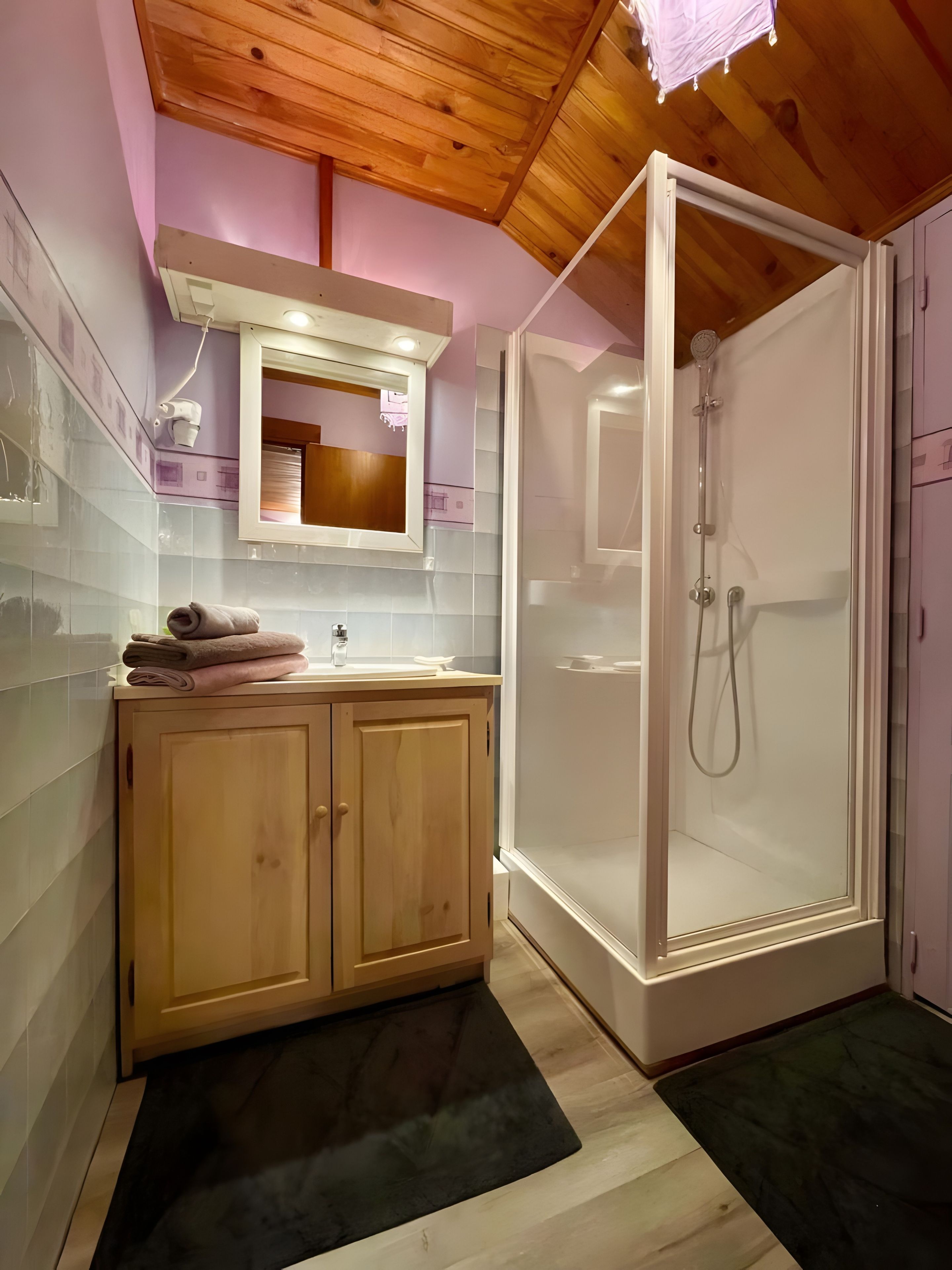 Une salle de bain avec un meuble en bois, un lavabo, un miroir et une douche à parois de verre.