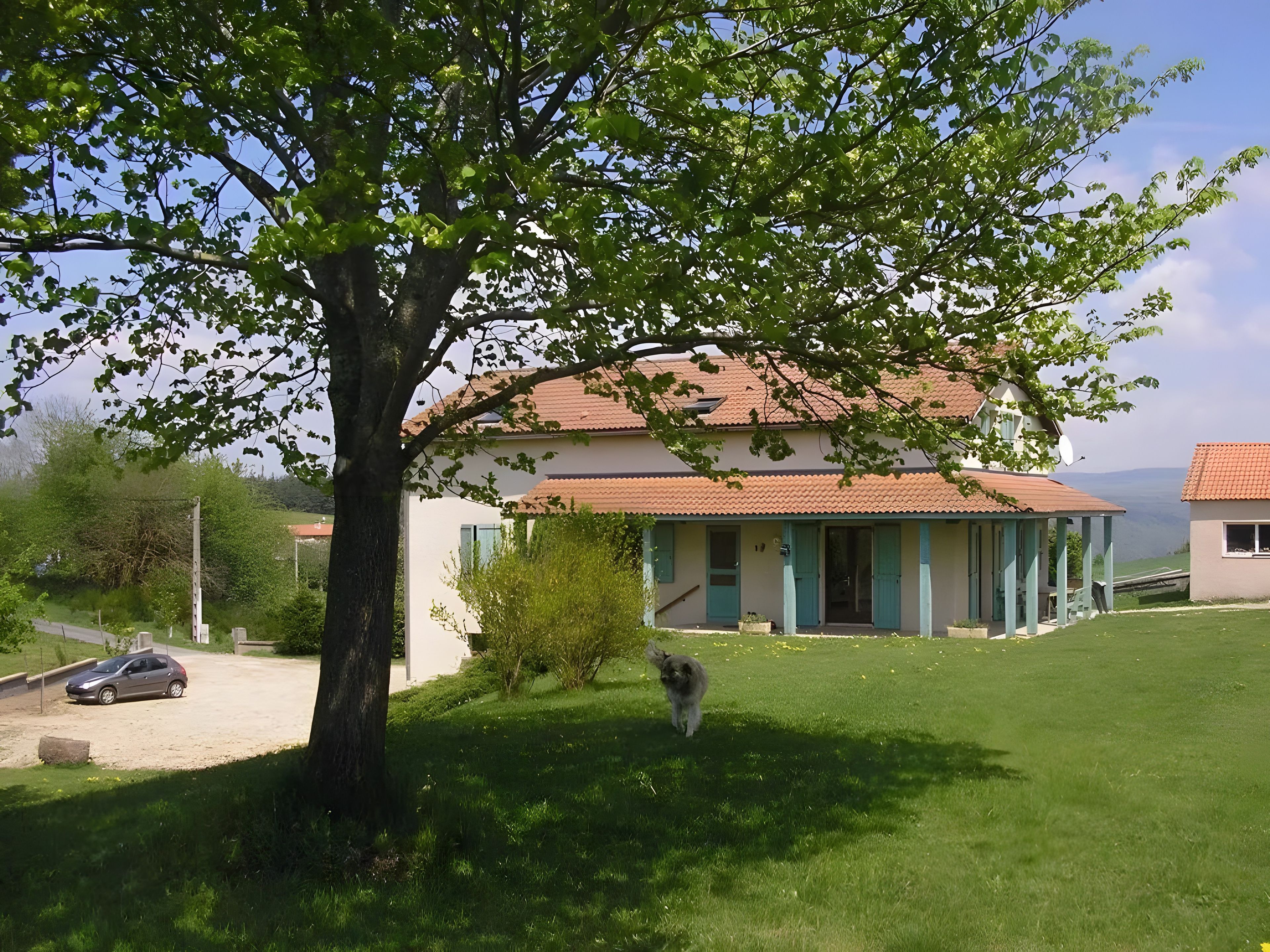 Ein Haus mit einem Ziegeldach, einem Rasen und einem Baum.