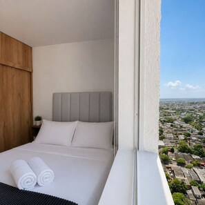 A hotel room with a bed, a view of a cityscape, and a window with a view of the city. - Royal Palm | Old Town Views, Marbella Beach & Pool (Cartagena)