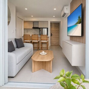 A modern living room with a sofa, a coffee table, and a TV mounted on the wall. - Royal Palm | Old Town Views, Marbella Beach & Pool (Cartagena)