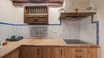 Une cuisine avec des meubles de rangement en bois, une cuisinière encastrée et un pare-feu décoré de carreaux bleus et blancs.