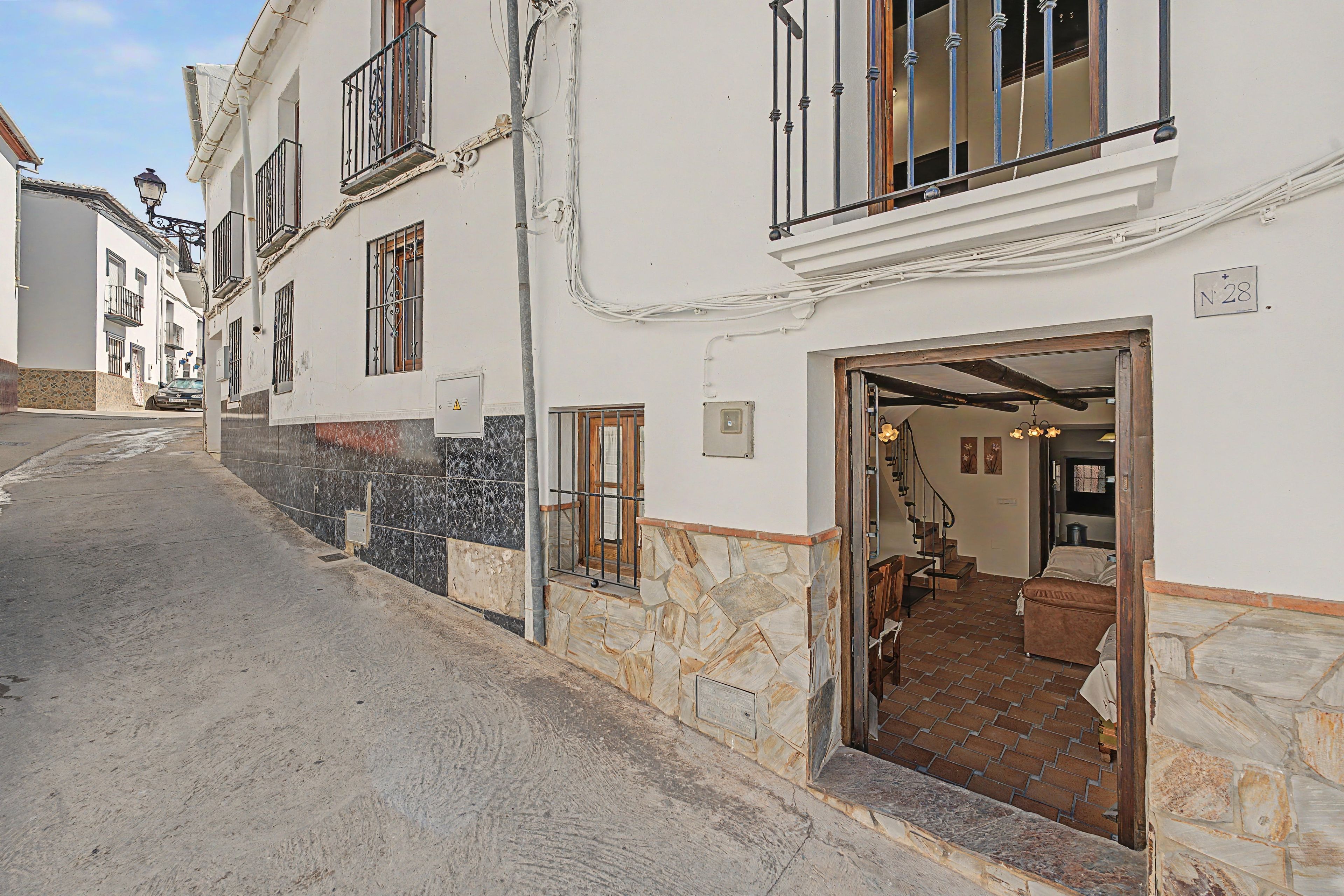 Une vue de rue d’un immeuble avec une fa çade en pierre, une porte en bois et un escalier menant à un étage supérieur.