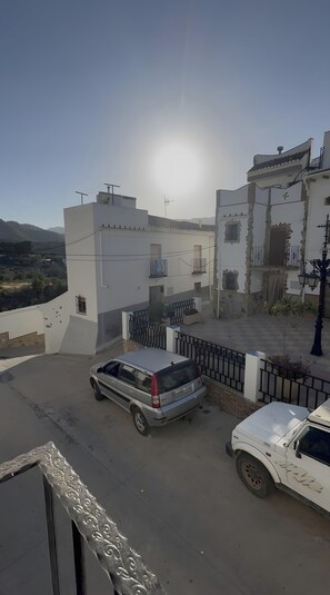A residential area with a parked car and a building with a balcony.