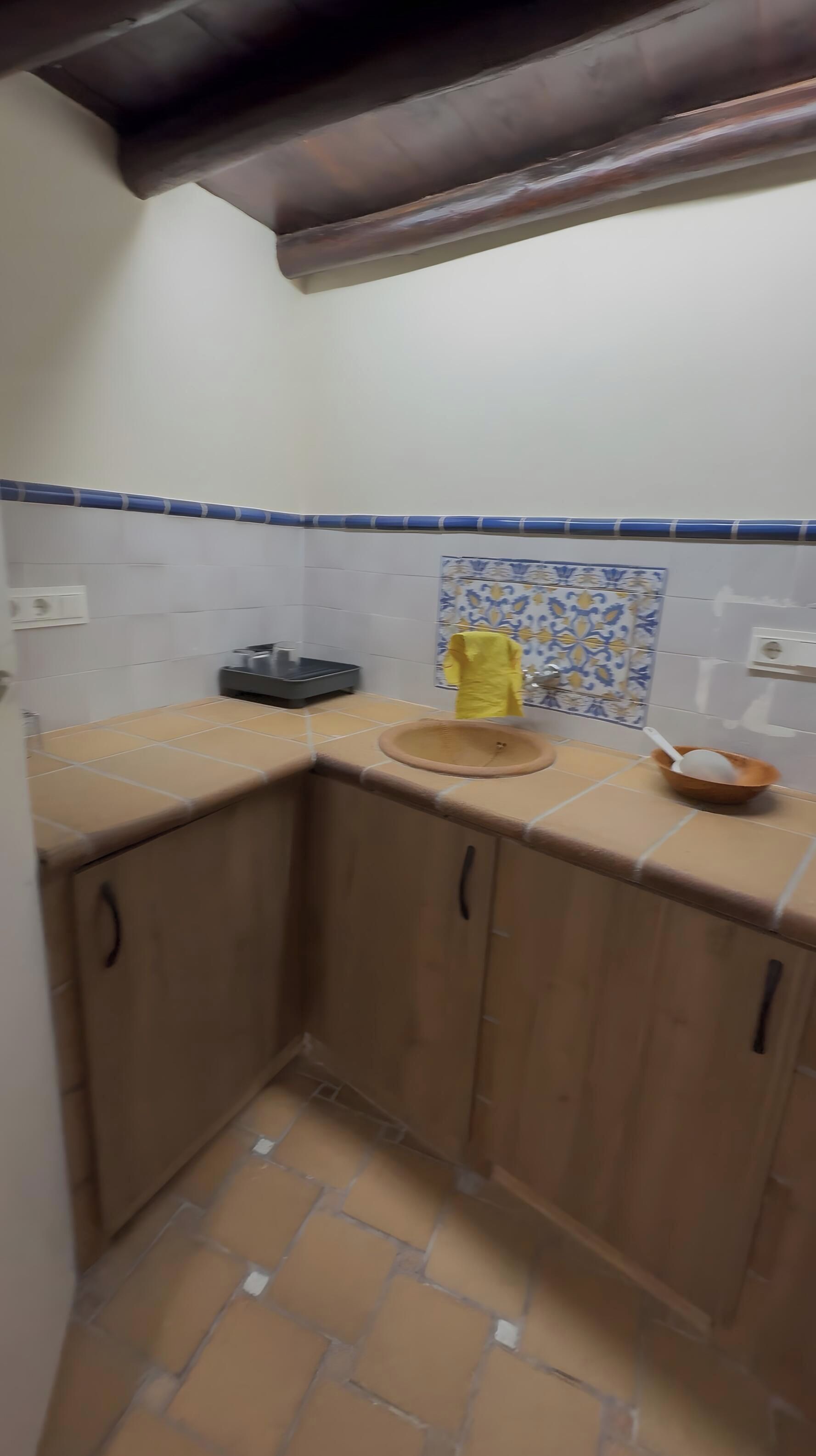 A small kitchen with a sink, a yellow towel, and a bowl on the counter.