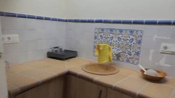 A small kitchen with a sink, a yellow towel, and a bowl on the counter.