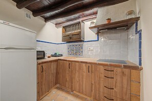 A kitchen with wooden cabinets, a built-in microwave, and a tiled backsplash.