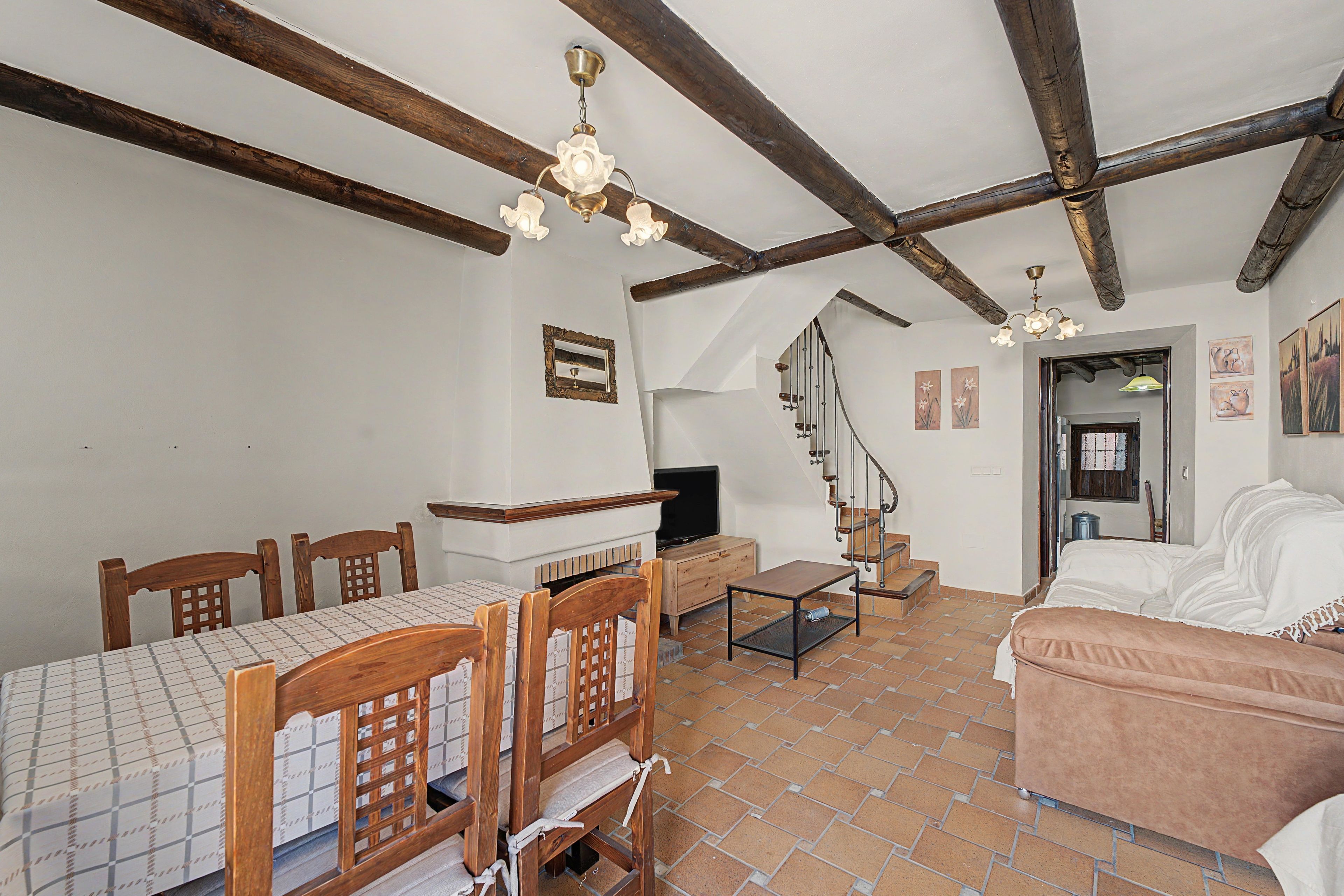Una habitación con una mesa de comedor, sillas, un sofá, un televisor y una escalera.