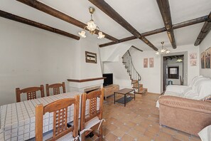 A room with a dining table, chairs, a sofa, a TV, and a staircase.