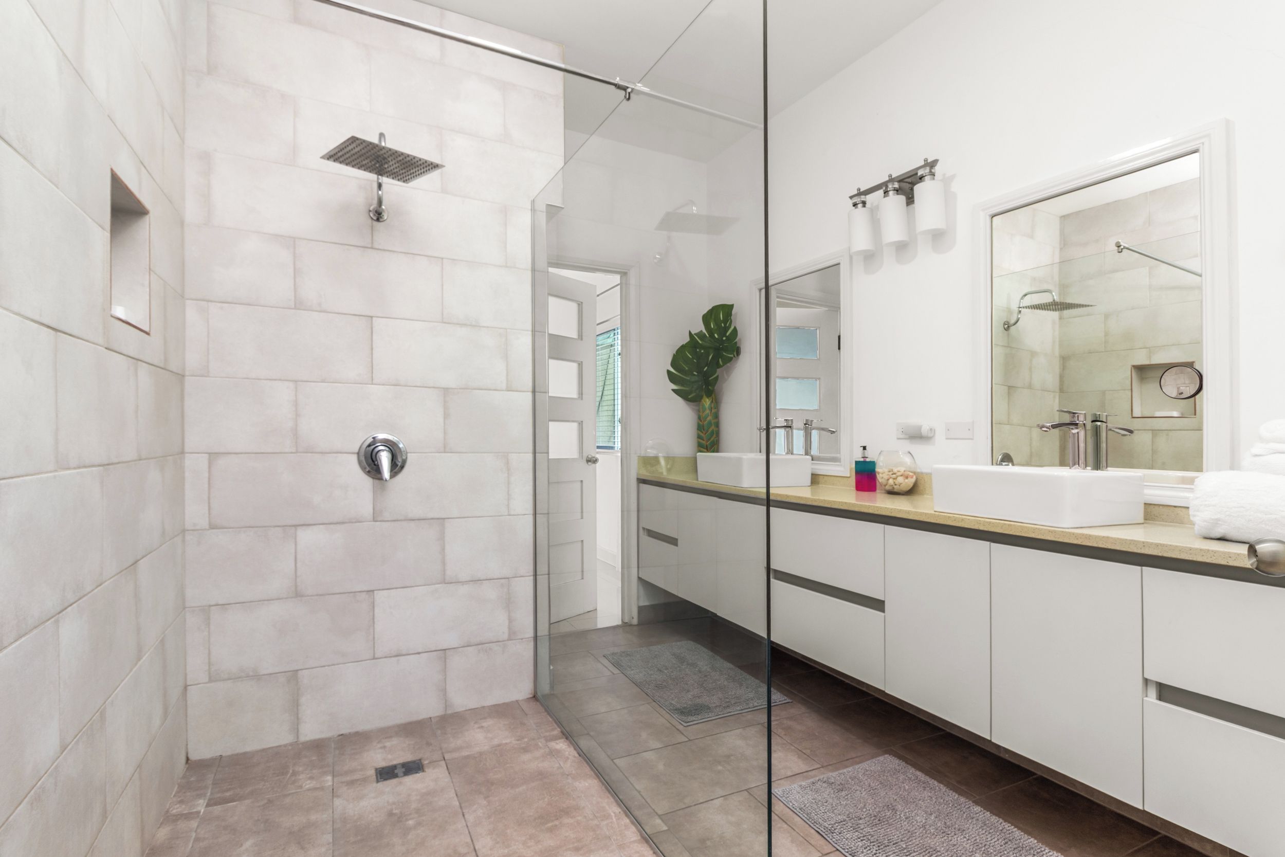 A modern bathroom with a glass-enclosed shower, a large mirror, and a vanity with a sink.