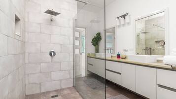 A modern bathroom with a glass-enclosed shower, a large mirror, and a vanity with a sink.