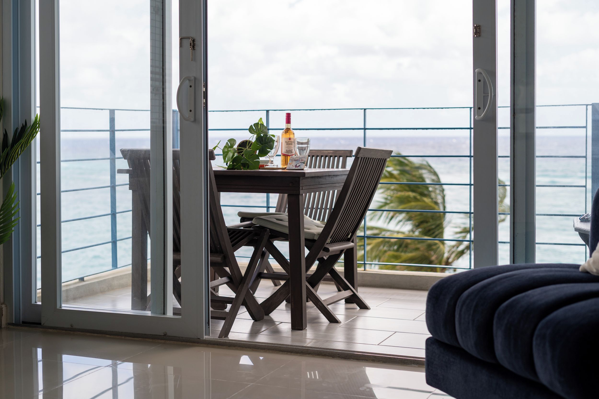 A balcony with a table and chairs, a bottle of Sutter Home wine, and a glass.