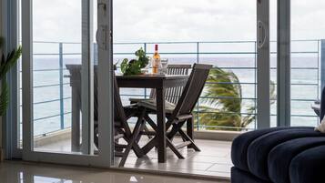 A balcony with a table and chairs, a bottle of Sutter Home wine, and a glass.