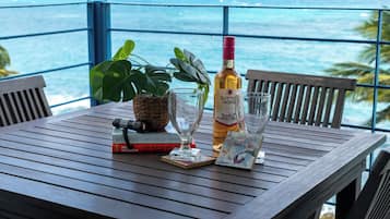A wooden table with a bottle of wine, a glass, a book, a camera, and a plant.