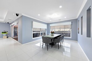 Ein moderner Essbereich mit Tisch und Stühlen, großen Fenstern und einer Decke mit Einbautenbeleuchtung.