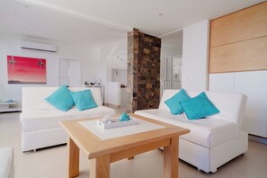 Een moderne woonkamer met twee witte banken, een houten salontafel en een accentmuur van steen.