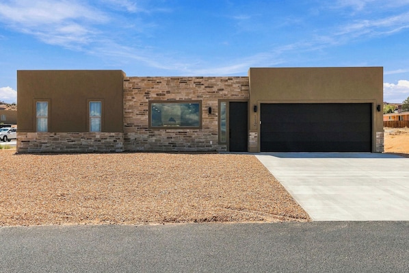 A modern two-story house with a stone facade, a garage, and a gravel driveway. - The Basecamp - 4BR Sleeps 14, Modern, Firepit (Page)