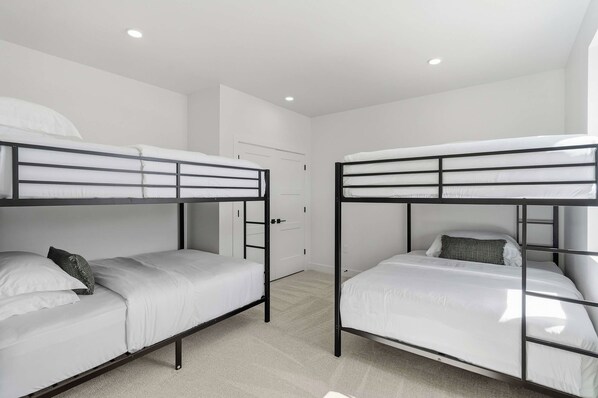 Ein Zimmer mit zwei Etagenbetten, einer weißen Tür und einem weißen Kleiderschrank.