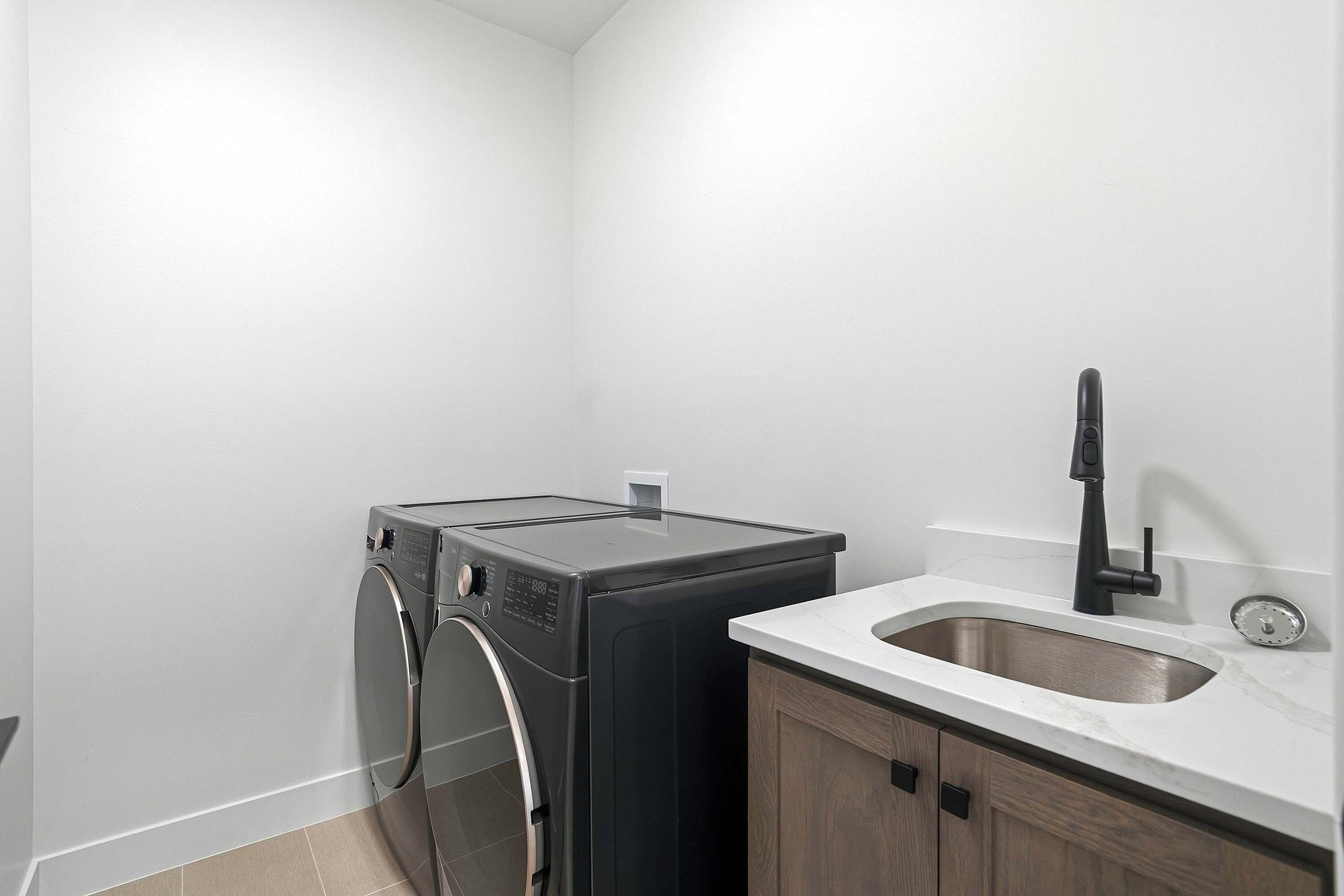 A laundry area with a washing machine, a sink, and a cabinet.