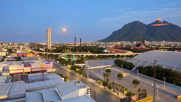 A cityscape with a prominent mountain in the background, a large industrial area with warehouses, and a highway with overpasses.