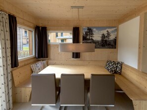A wooden interior with a large table, four chairs, and a bench. - One-bedroom Cabin (Sankt Georgen am Kreischberg)