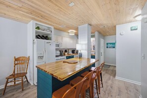 A kitchen with a wooden island, white cabinets, and a blue accent wall. - Coastal Retreat at Beachwalk, Steps from the Gulf (Panama City Beach)
