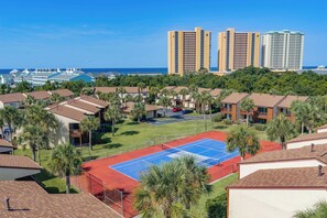 A residential area with multiple-story buildings, a tennis court, and a view of the ocean. - Coastal Retreat at Beachwalk, Steps from the Gulf (Panama City Beach)