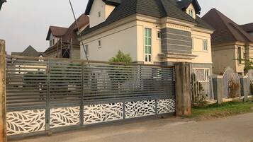 A residential building with a gated entrance, a sloped roof, and a decorative fence.