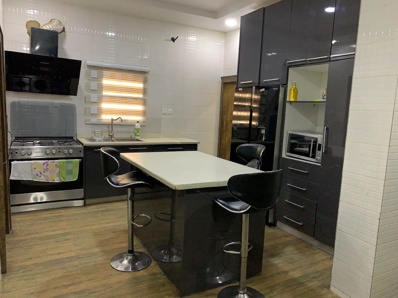 A compact kitchen with a built-in oven, a microwave, and a bar stool area.