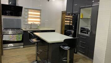 A compact kitchen with a built-in oven, a microwave, and a bar stool area.